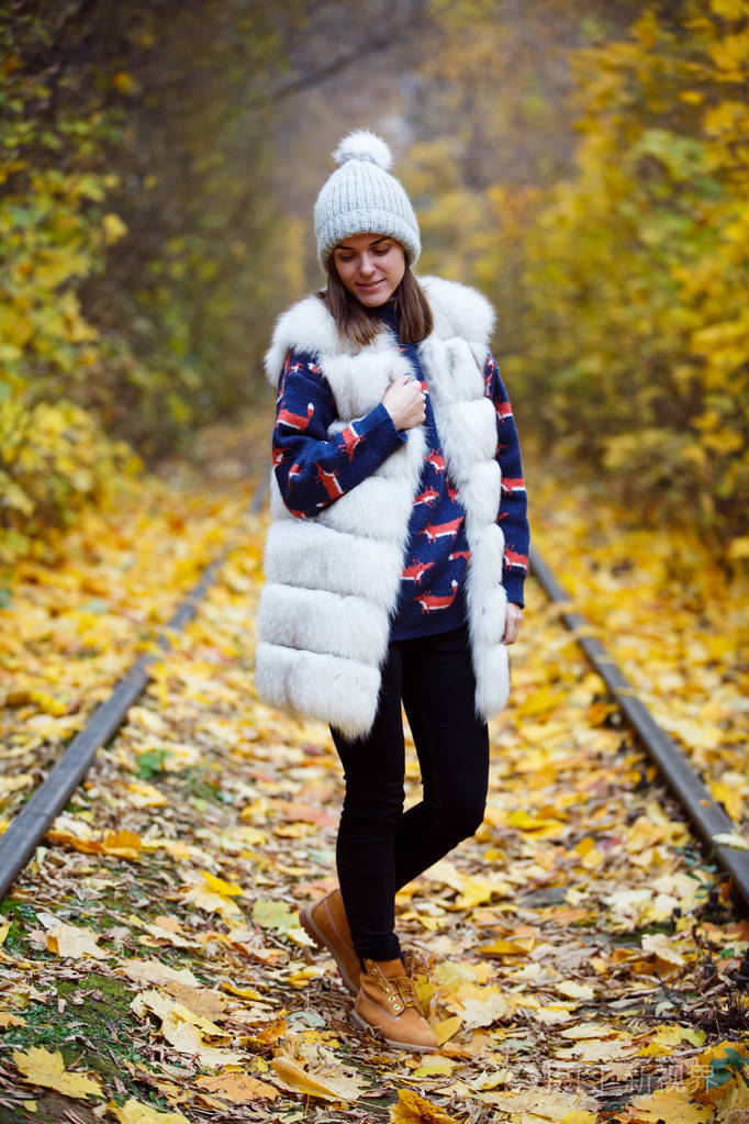 帽子和围巾户外在秋天的自然背景中微笑的年轻女子照片-正版商用图片0