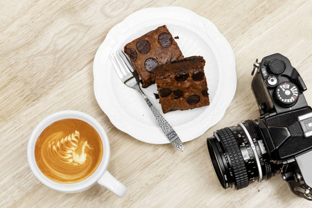 巧克力布朗尼咖啡拿铁咖啡休息和老式相机上早饭中规中矩