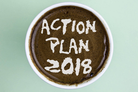 编写显示行动计划2018的说明。商业照片展示做列表在新年新年决心的目标在咖啡杯上的普通背景
