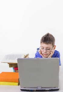 可爱的小学生的肖像坐在笔记本电脑键盘上打字