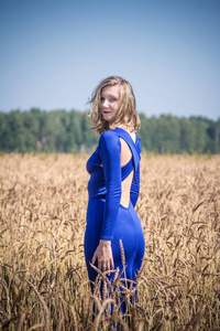 一个穿着蓝色连衣裙的女孩在田野里走动。