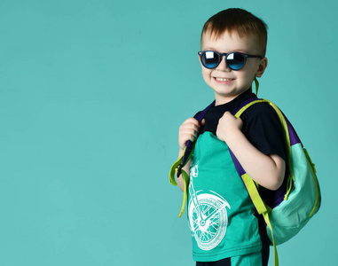 幼儿园男孩与背包和太阳镜站在短裤和 t恤上的绿色薄荷