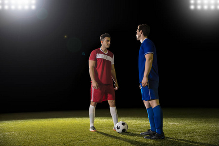 两名职业足球运动员在比赛中面对面地站在足球场上