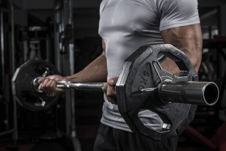 肌肉建设者人训练他的身体与杠铃在现代健身中心