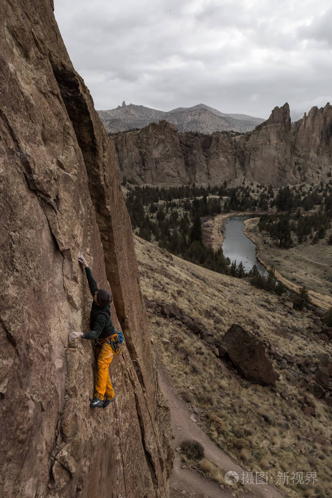 冒险的人是攀岩在陡峭的悬崖边在一个多云的冬季傍晚拍摄于美国俄勒冈