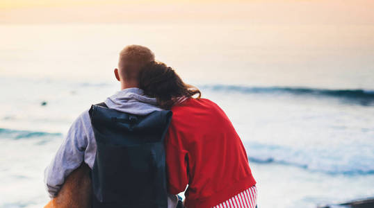 情侣相拥在海滩上的海边日出, 剪影两个浪漫的人拥抱和看后景色的傍晚