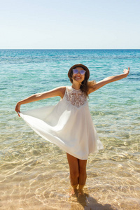 快乐的女人在夏天白色礼服在海滩上。女孩放松和享受和平在假期