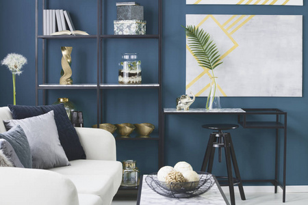 金象和一个玻璃花瓶里的叶子放在蓝色起居室内的大理石桌上, 装饰在金属架子上