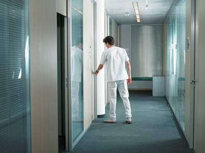 男医生在大厅开门正在推开门的残疾人人开门,特写,背景模糊.