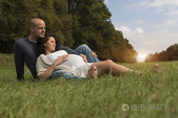 坐在公园草地上的怀孕夫妇