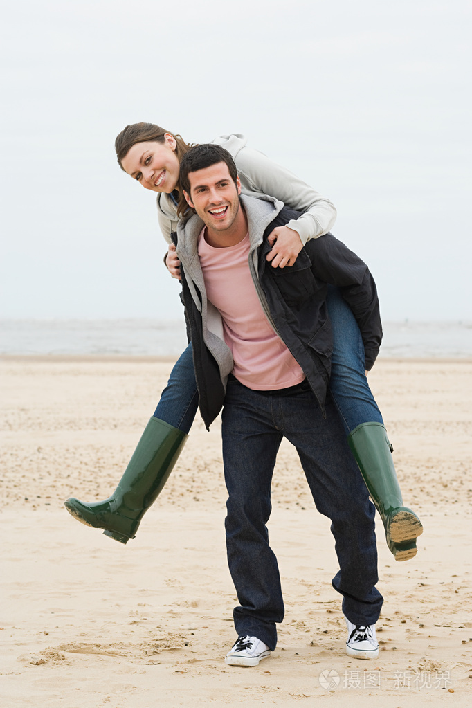 男人在沙滩上背着女人