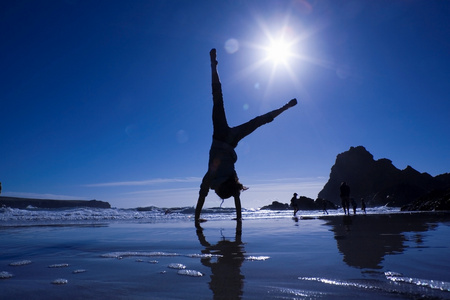 做倒立的少女穿黑色运动服的强壮女人在海边做倒立在海边做倒立的女孩