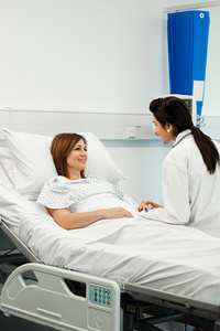 年轻医生为患病的老年妇女患者提供片剂信息治疗孕妇在病床上分娩患者