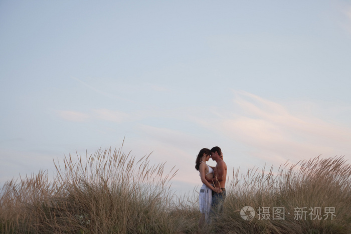 一对情侣在海边的芦苇丛中接吻