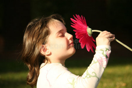 天真地闻到花香的孩子照片