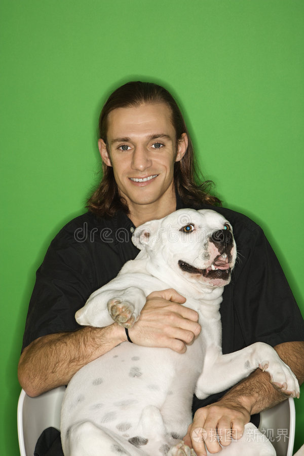 一个年轻人抱着白色的狗在膝上。