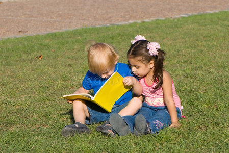 小男孩和女孩在公园的空地上读图片