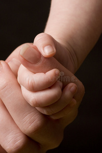 婴儿的手抓住成人的手指