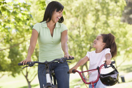 在户外骑自行车的女人和小女孩微笑着