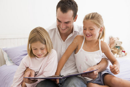卧室里的男人和两个小女孩在看书