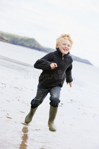小男孩微笑着跑在沙滩上