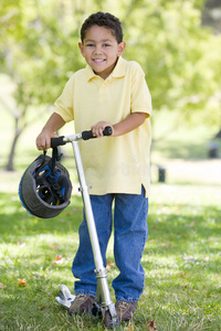 小男孩在户外骑着滑板车微笑