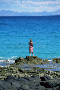 站在岩石上眺望大海的年轻女子
