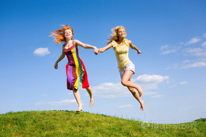 两个快乐的女孩在草地上逃跑