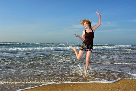 沙滩上一个金发女人拿着手机跳舞