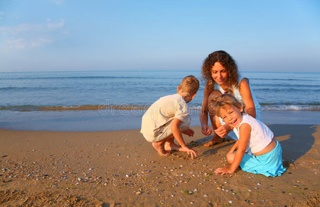 妈妈和孩子们在沙滩上玩寻找贝壳
