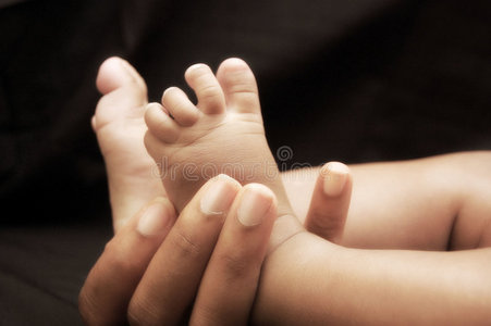 女人的手抱着婴儿的脚