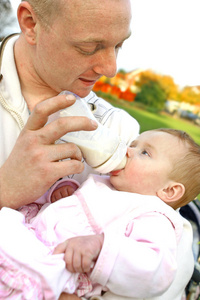 父亲用一瓶牛奶喂他的女婴