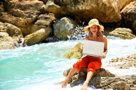 在海边用笔记本电脑的年轻女子