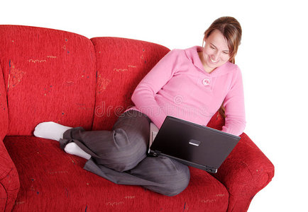 年轻妇女拿着笔记本电脑躺在沙发上