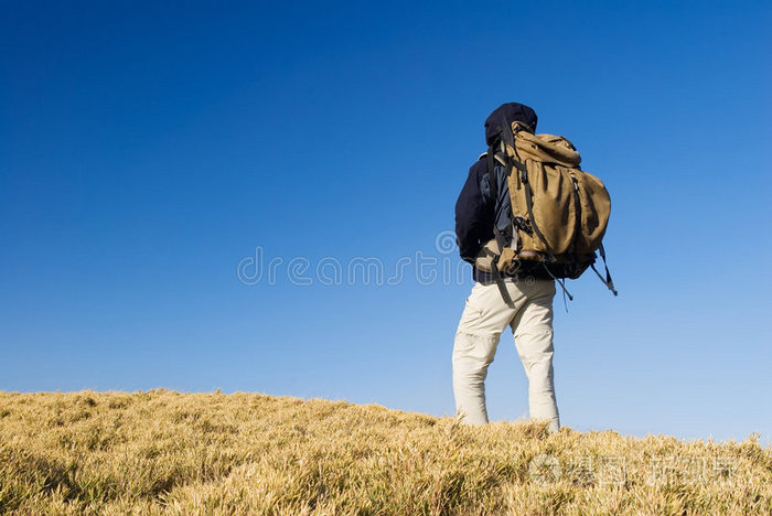 一个背包客在山上的黄色草原上散步