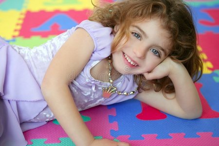 美丽的公主小女孩微笑着躺在地板上