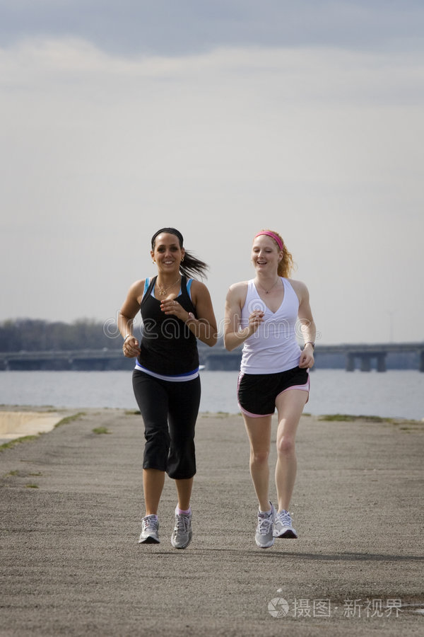 奔跑公园慢跑沿水跑步的年轻人慢跑积极的女人休息两个年轻女子一起