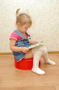 小女孩坐在红色便盆上，打开书本