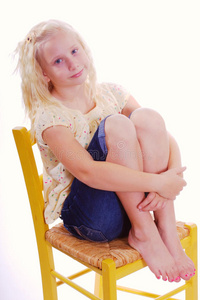 坐在黄色椅子上抱着双腿的女孩照片