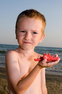 这个男孩抱着一只红海星