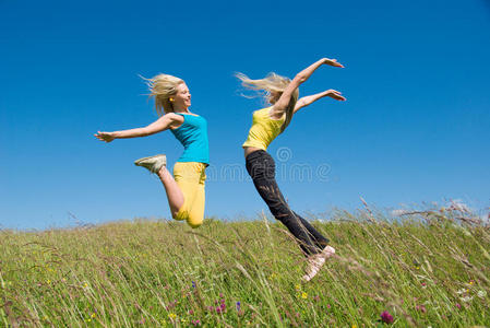 在草地和蓝天上跳跃的女人