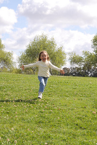 在公园草坪上跑步的小女孩