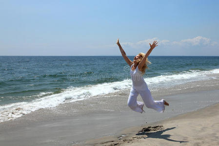 快乐的女人在沙滩上跳