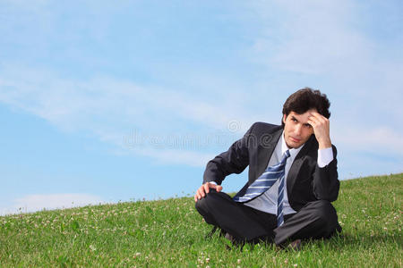 坐在草地上思考的商人