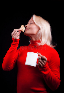 漂亮的金发女郎拿着杯子和饼干