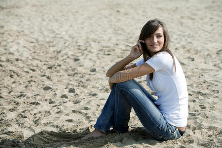 坐在沙滩上拿着手机的女人