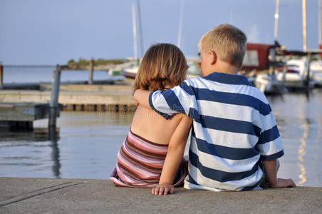 坐在码头上的小男孩和小女孩