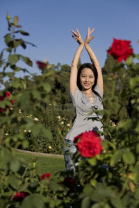 美丽的亚洲女孩在红玫瑰中翩翩起舞