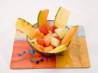 把新鲜水果沙拉放在碗里，放在白色背景的垫子上。