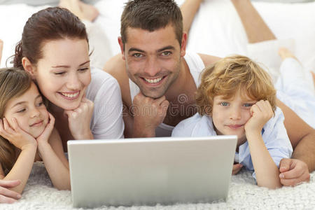 父母和孩子在床上用笔记本电脑